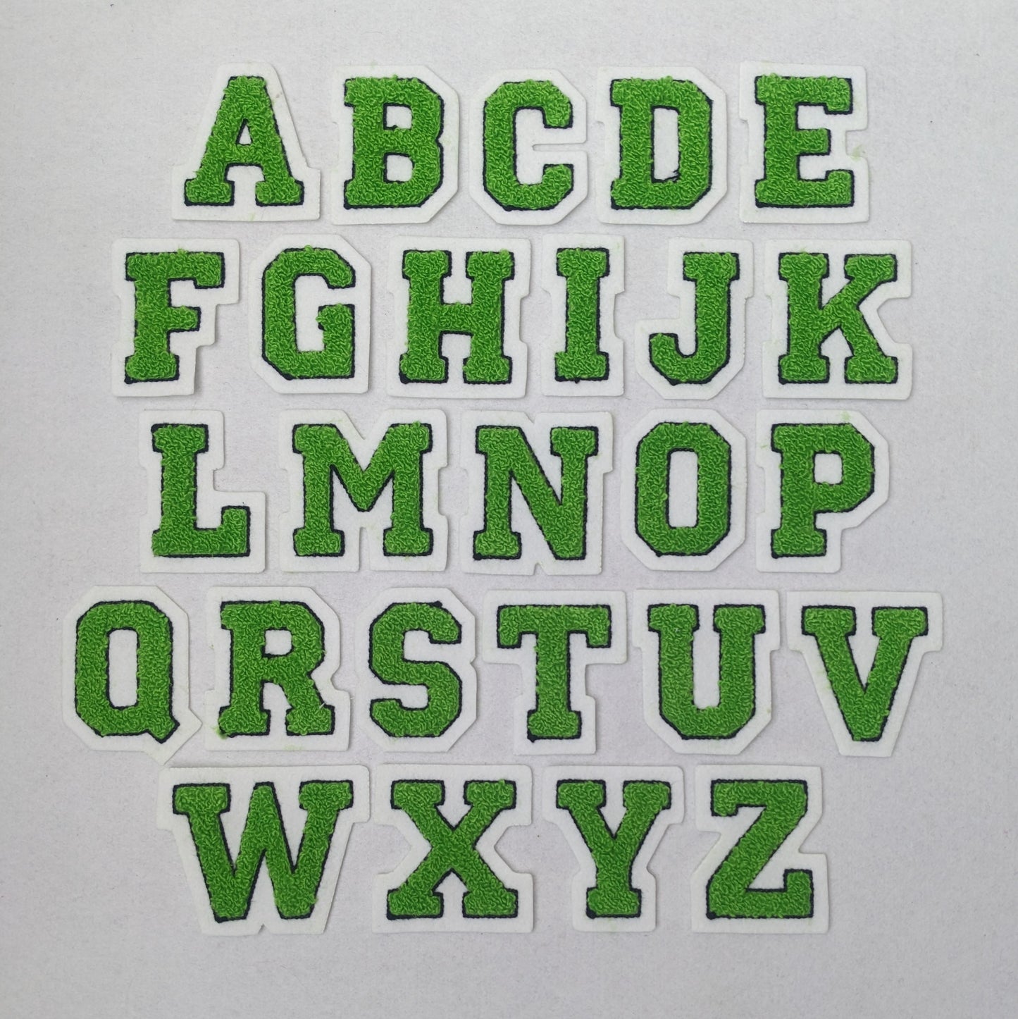 Lime green chenille block letter with black outline on white colored felt.