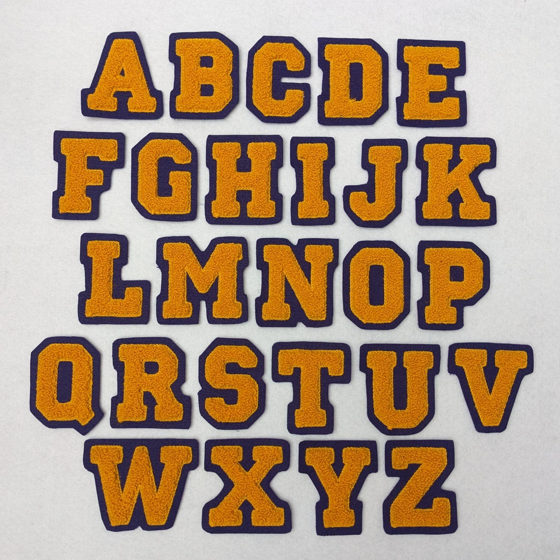 Athletic gold chenille block letter on purple colored felt.