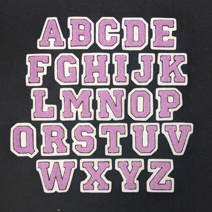 Lavender chenille block letter with black outline on white colored felt.