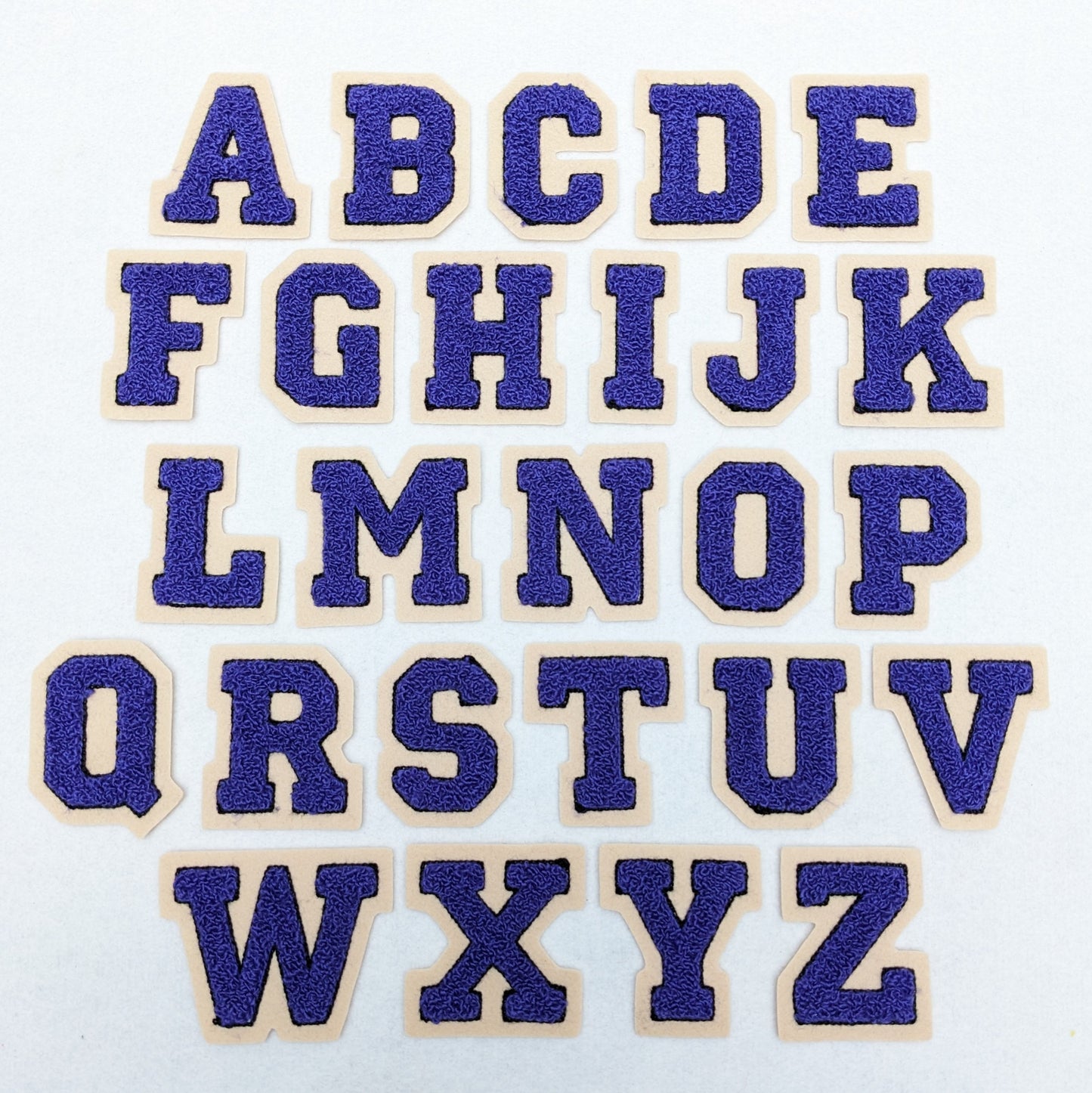 Purple chenille block letter with black outline on champagne colored felt.