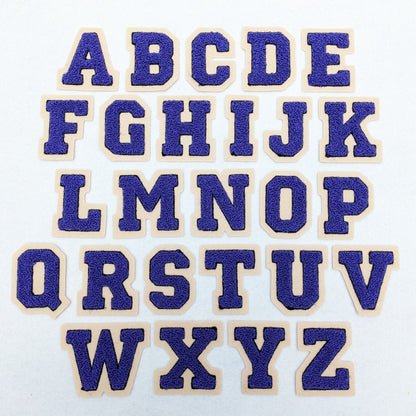 Purple chenille block letter with black outline on champagne colored felt.