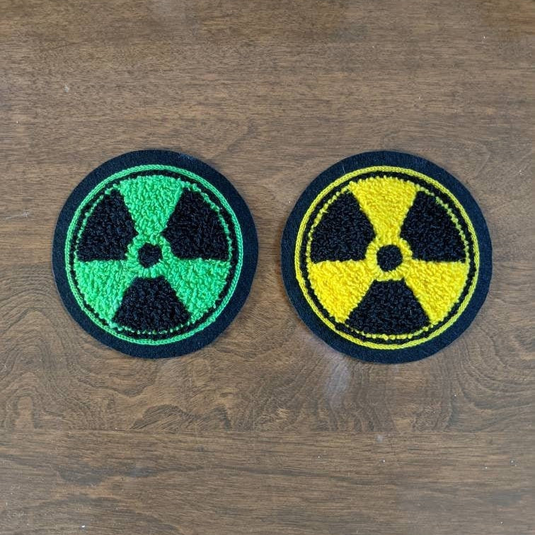 Two embroidered patches with radiation symbols on a wooden surface